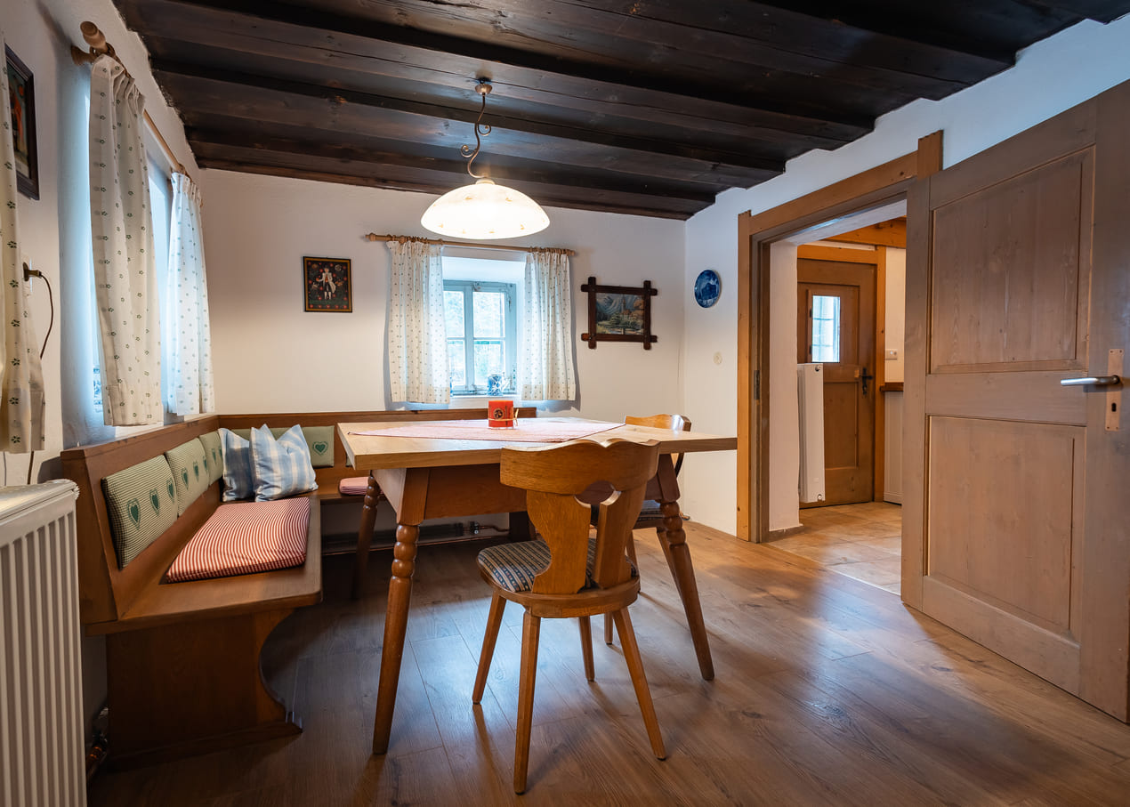 Gemütliche Stube der Scharitzkehlalm mit hölzerner Eckbank und gestreiften Sitzkissen