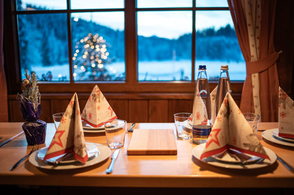 Weihnachtlich gedeckter Holztisch für vier Personen in einer gemütlichen Stube